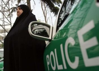 Mujer con hiyab y automóvil de la policía