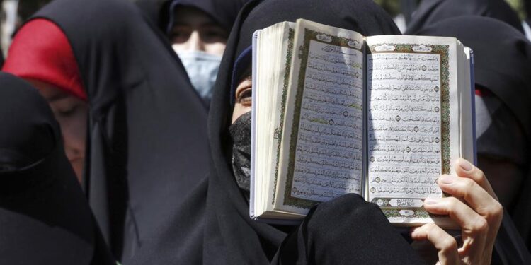 Mujeres con velo islámico y un Corán abierto